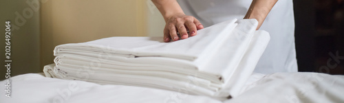Foto Close up of woman folding clean bed sheets on bed, preparing hospitality linen service