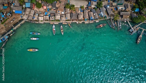 Aerial view of a small tropical harbor with boats and coastal houses along the shore