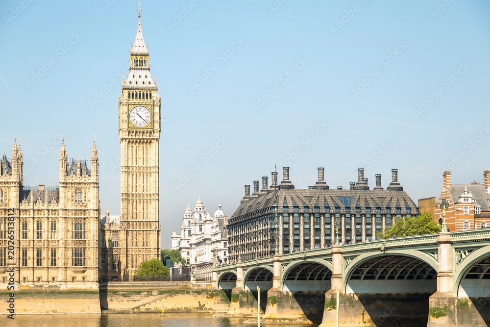 Obraz premium An iconic view of the Elizabeth Tower, commonly known as Big Ben, stands prominently alongside the Palace of Westminster and Westminster Bridge overlooking the River Thames in London.