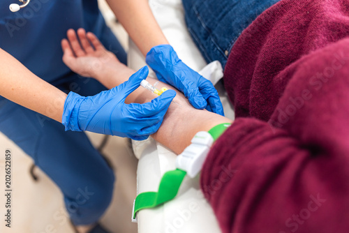 Nurse inserting IV cannula needle into patient arm for blood test or infusion. Medical procedure, hospital treatment, healthcare, blood donation, clinic checkup and laboratory analysis concept.