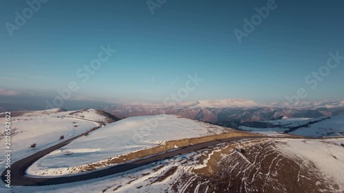 Aerial view of snow-covered hills and winding road in mountainous landscape