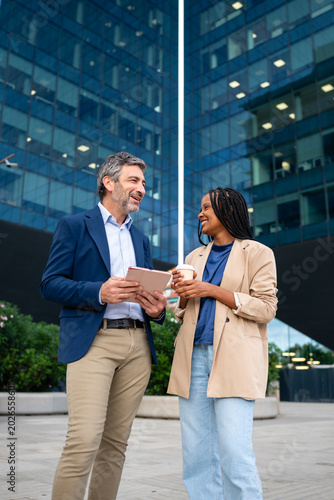 Diverse business people discussing outdoors with tablet