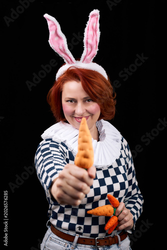 Smiling woman in bunny ears costume holding carrots playfully posing