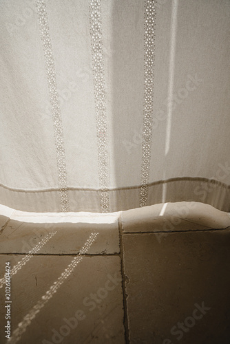 Fotografía Bottom Hem Of Sheer Embroidered Curtain Touching Stone Tile Floor