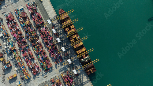 Aerial drone shot of crane loading containers onto cargo ship at Laem Chabang Port.