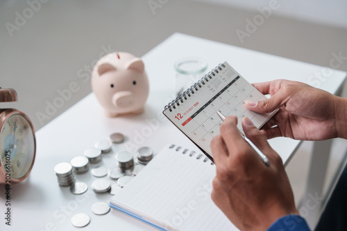 Foto Asian man planning schedule with calendar, pen, and savings on desk