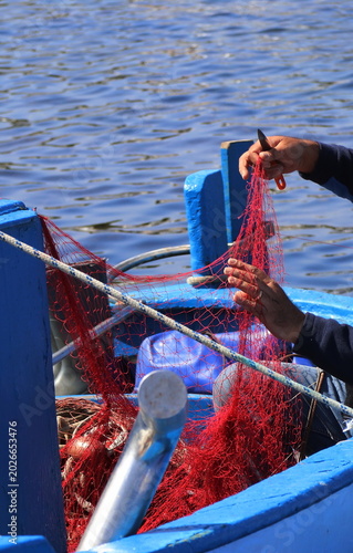 un pescatore mentre ripara la propria rete da pesca la propria