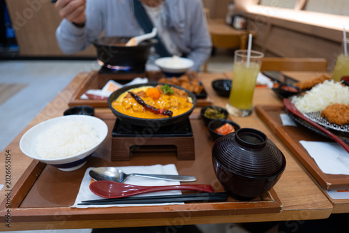 Fotografi Crop anonymous man with chopsticks eating yummy Kimchi Soup in hot bowl at Japanese restaurant