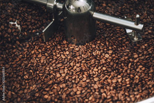 Canvastavla Close-up view of freshly roasted coffee beans inside a commercial roaster machine, showing the rich brown color and texture of the beans