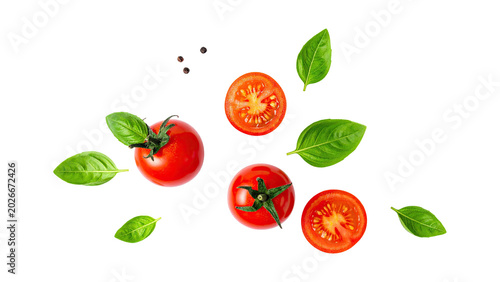 Obraz na plátně Cherry tomatoes and basil leaves falling on black background top view
