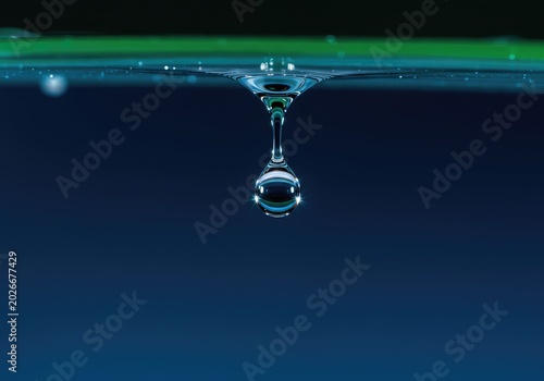 Extreme close-up of a perfectly formed water droplet hanging precariously, reflecting light and demonstrating the fragile purity of nature and moisture ,cool ,pure ,moisture