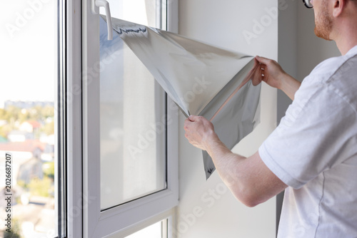 Man takes sun protection film off from the windows glass.