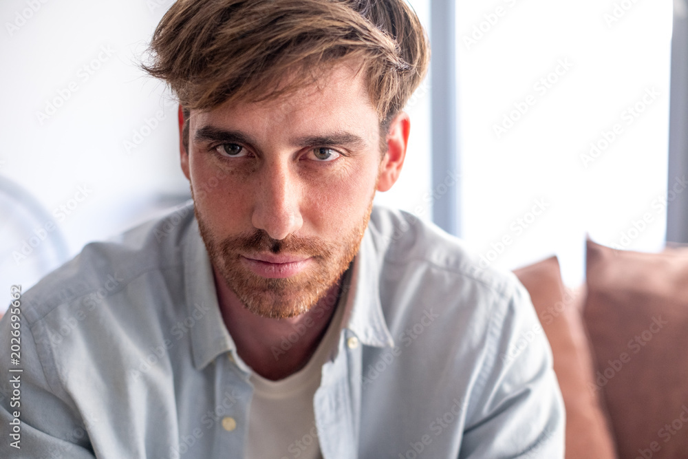 Obraz premium Serious Young Man Casual Portrait At Home Close-Up Headshot With Beard And Blue Shirt