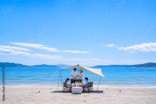 晴れた日の海辺でバーベキューを楽しむ家族の夏休みと思い出のアウトドアイメージ（AI生成）