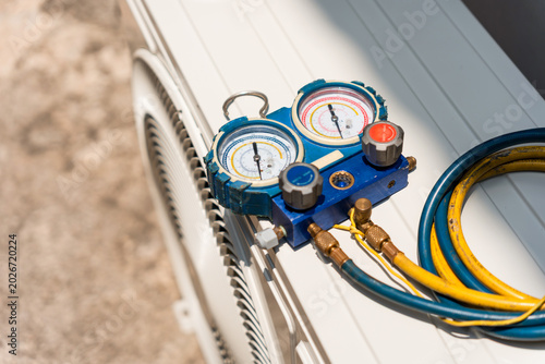 Fotografie Hvac manifold gauge set on top of outdoor air conditioning unit, refrigerant man