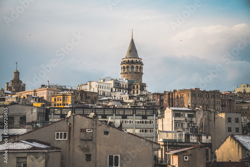 Galata Tower is captured from street level, rising between close buildings and creating a narrow vertical frame.