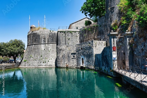 Kotor, Montenegro. Ancient stone fortress walls reflected in the clear turquoise water of a moat