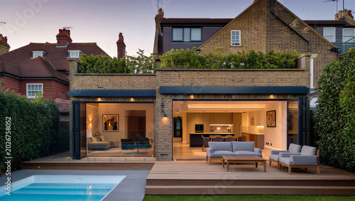 Foto Luxury house at dusk with illuminated open plan extension swimming pool living r