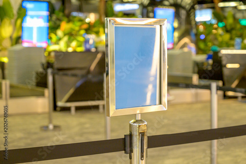 фотографія Close-up of a blank silver sign holder on a retractable belt barrier stanchion in a modern airport terminal or public hall