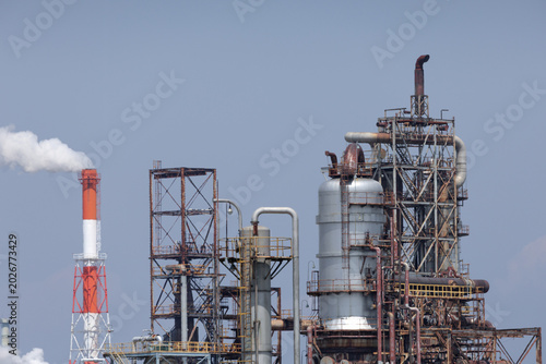 Industrial refinery complex with distillation columns linked to steel piping network in petrochemical processing facility, illustrating energy production and ecological impact in industrial landscape.