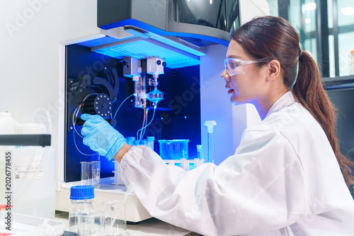 Scientist in protective gear operates advanced laboratory equipment with blue illumination