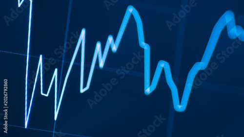 Bild auf Leinwand Close-up of a digital stock market chart with a volatile blue line on a screen