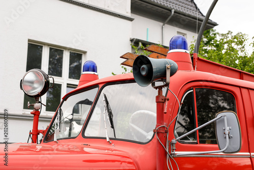 Close-up view of vintage red fire truck features, siren, and spotlight