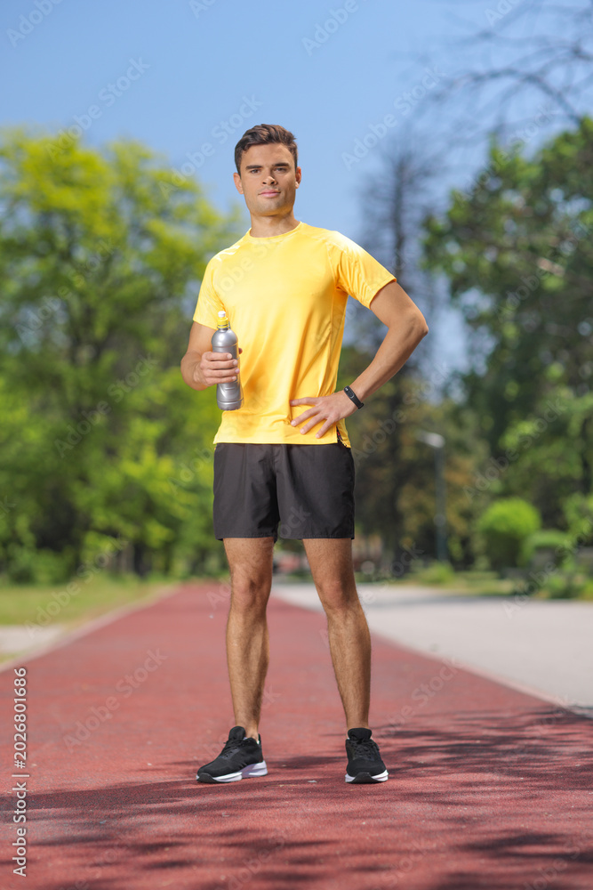 Naklejka premium Young man standing on an outdoor running track