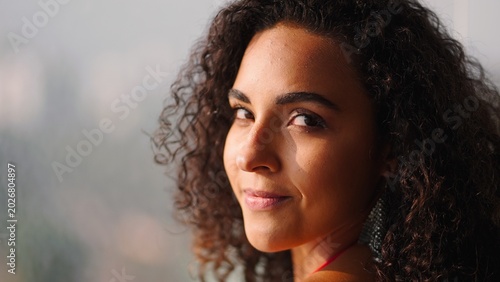 Fotografie Young woman with beautiful curly hair smiling, looking at camera