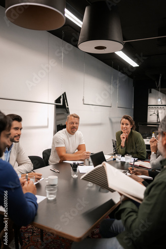 Male business expert discussing ideas with coworkers during meeting in office