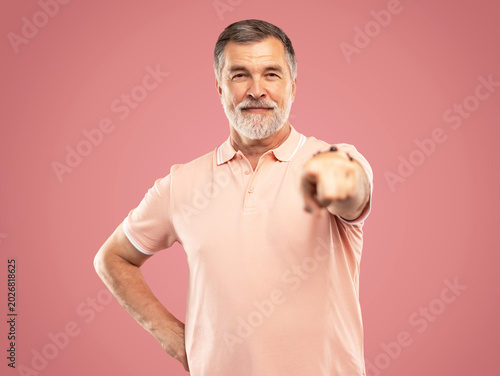I choose you and order. The smiling mature businessman point you, portrait on pink studio background