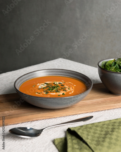 Bowl of fresh pumpkin soup served on table