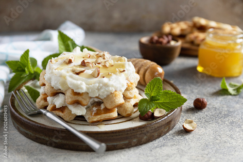 Belgian waffles with ricotta cheese, honey and hazelnuts for breakfast on a stone background. Sweet breakfast gluten free. Summer homemade recipe.