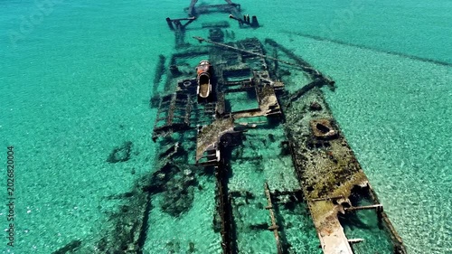 Aerial view of the famous Epanomi shipwreck submerged in crystal clear turquoise waters near the sandy beach spit in Halkidiki, Greece.