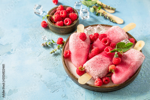 Healthy summer food concept, homemade raspberry ice cream. Vegan raspberry milk popsicles on a blue stone background. Copy space.