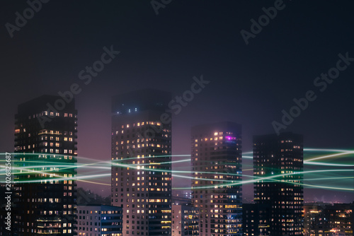 Digitally generated image of network lines passing through illuminated buildings under clear sky at night