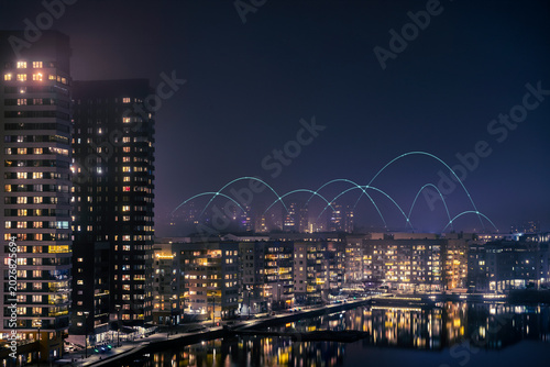 Digitally generated image of network lines above illuminated city buildings against clear sky