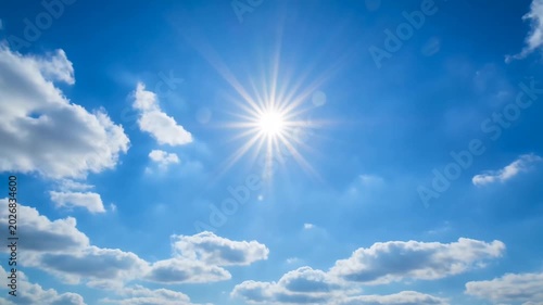 A timelapse capturing the sun’s rays shining through moving fluffy cumulus clouds in a bright blue summer sky.
