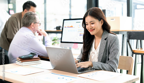 Happy Asian Businesswoman Smiling While Working on Laptop
