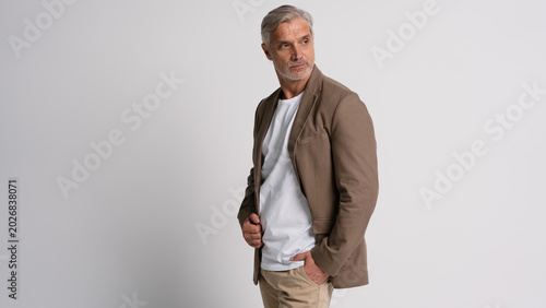Serious middle-aged man posing in front of a grey background with copy space.