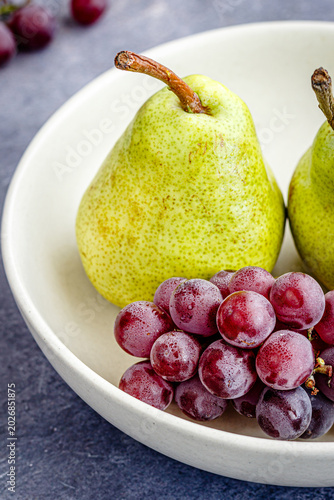 Close Up of Fresh Pears and Red Grapes in Ceramic Bowl on Rustic Background