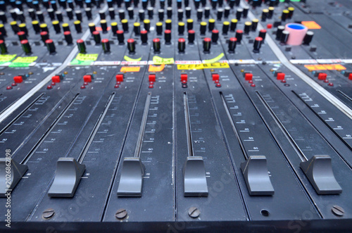 faders and control buttons on a professional analog sound mixing console in a television studio