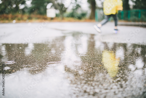 Fotografia Child walking near puddle on rainy day with soft reflection