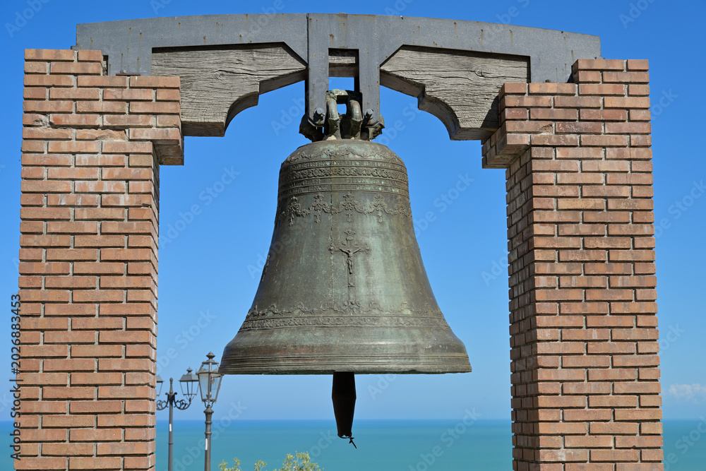 Obraz premium Vasto campana San Pietro ringing overlooking the Adriatic Sea. Bronze bell hanging in brick frame against blue sky and sea providing a historical view.