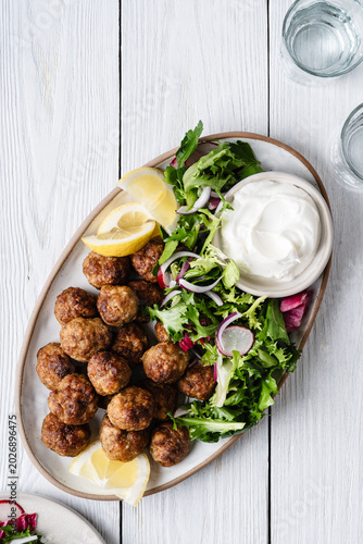 Meatballs served green salad and yogurt based dip on tray, comfort food