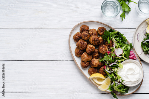Meatballs served green salad and yogurt based dip on tray, comfort food
