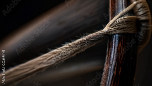 taut. Extreme close-up of a taut bowstring stretched against a dark wooden bow. event key visuals, club posters, designed for sports event promotions and stadium branding, supports training.