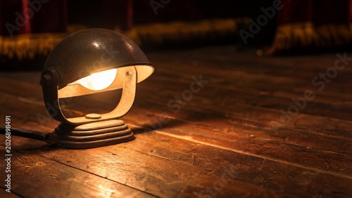 footlight. Vintage footlight with warm glow illuminating wood grain of a stage floor. gardening catalogs, home-decor guides, designed for gardening and botanical catalogs, promotes healthy living.
