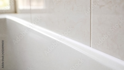 caulk. A close-up of a smooth white caulk sealant bead at a bathtub and tile junction. real-estate listings, architecture portfolios, designed for interior renovation comparisons for interiors.
