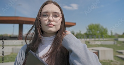 Fotografi A hand-held portrait of a young female student in casual clothes, wearing glasse